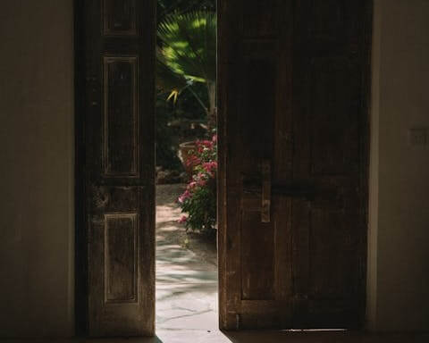 Porte ancienne entrouverte laissant entrer la lumière, symbole de passage, de transformation et de transition